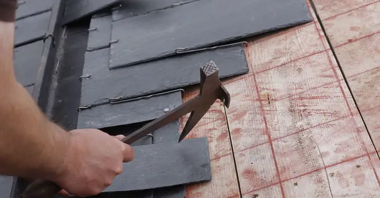 Zoom sur les mains d’un homme installant une toiture en ardoise