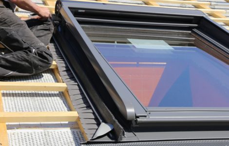 Un homme installant des tuiles rouges naturelles sur le toit