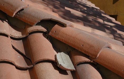 Vue sur une toiture en tuile avec une partie de tuiles cassées