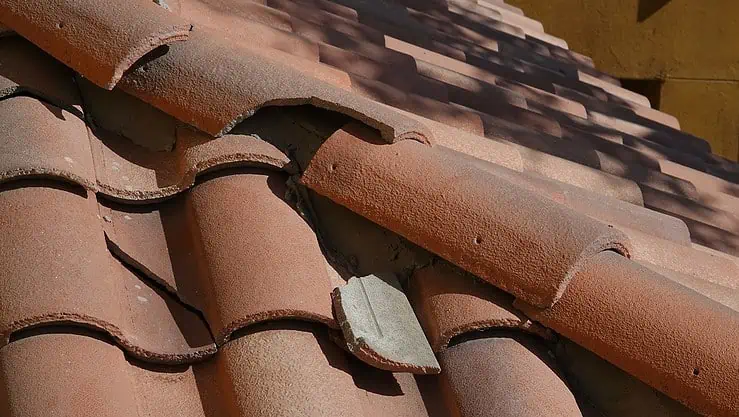 Vue sur une toiture en tuile avec une partie de tuiles cassées