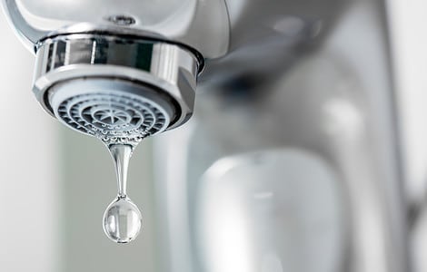 Gros plan d'un robinet avec une goutte d'eau