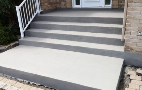 Un escalier en béton rénové devant la porte principale d’une maison