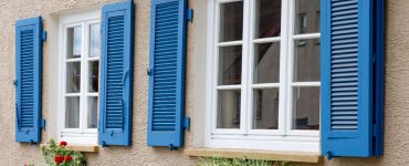 Deux fenêtres avec cadres en bois blanc et volets bleus