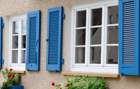 Deux fenêtres avec cadres en bois blanc et volets bleus