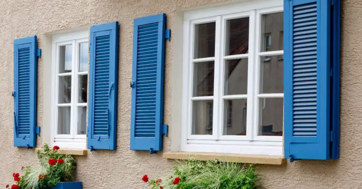 Deux fenêtres avec cadres en bois blanc et volets bleus