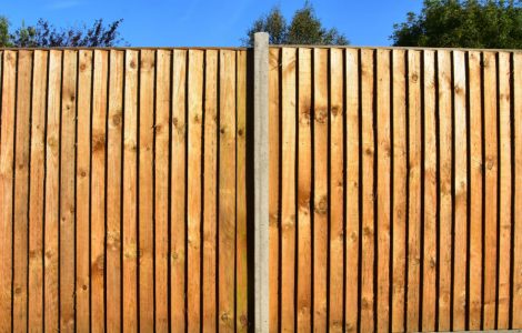 Une clôture de jardin en bois avec des poteaux d'appui en béton