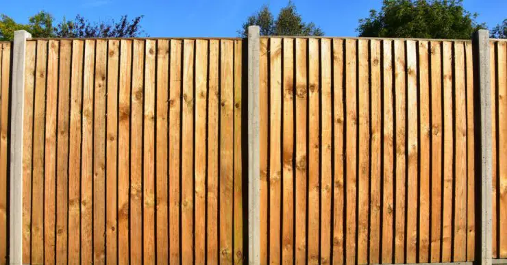 Une clôture de jardin en bois avec des poteaux d'appui en béton