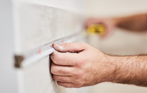 Zoom sur les mains d'un homme prenant des mesures à l'aide d'un mètre ruban
