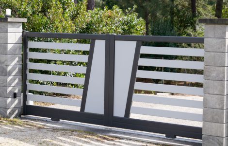 Un portail gris et blanc coulissant donnant sur un jardin