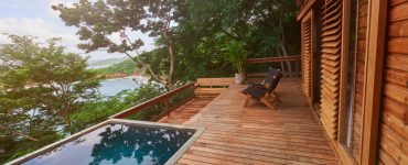 Une maison en bois avec une terrasse en bois et une piscine extérieure