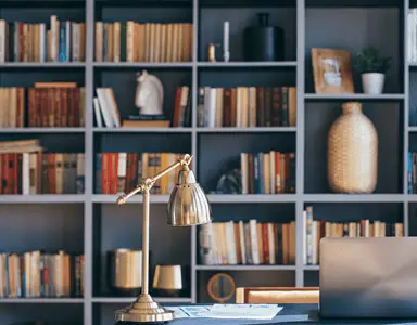 Un ordinateur portable posé sur un bureau bleu, avec une bibliothèque en fond