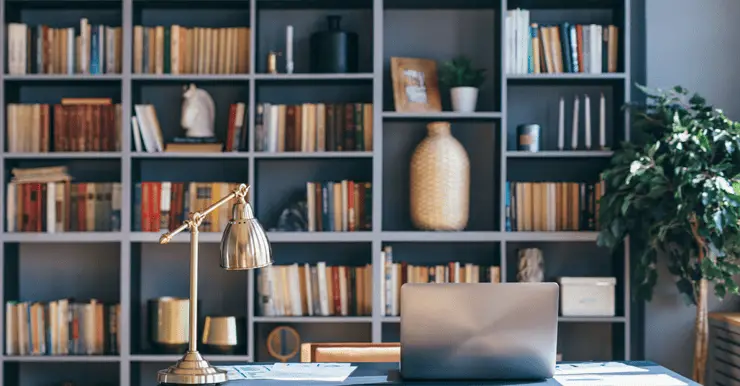 Un ordinateur portable posé sur un bureau bleu, avec une bibliothèque en fond