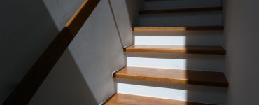 Lumière du soleil sur un escalier en bois avec une main courante en bois