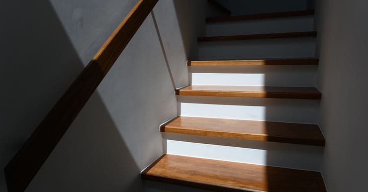Lumière du soleil sur un escalier en bois avec une main courante en bois