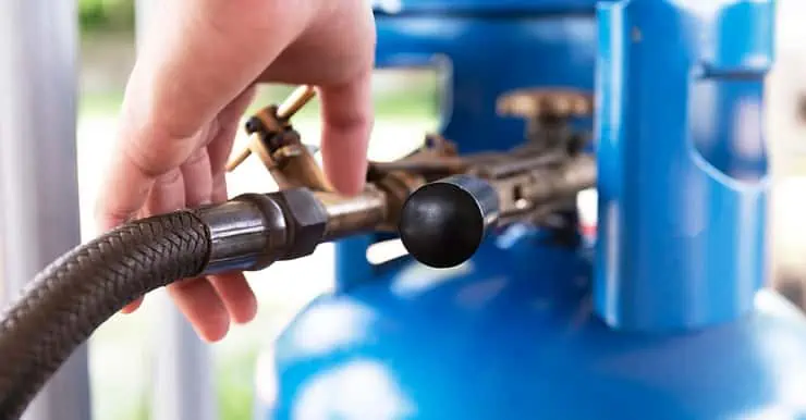 Zoom sur la main d’un homme touchant une bouteille de gaz destinée à la cuisine