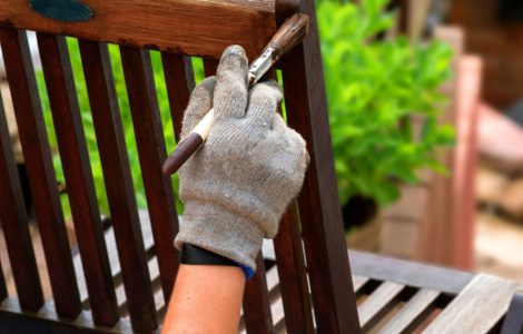 Main d’une personne peignant une chaise en bois