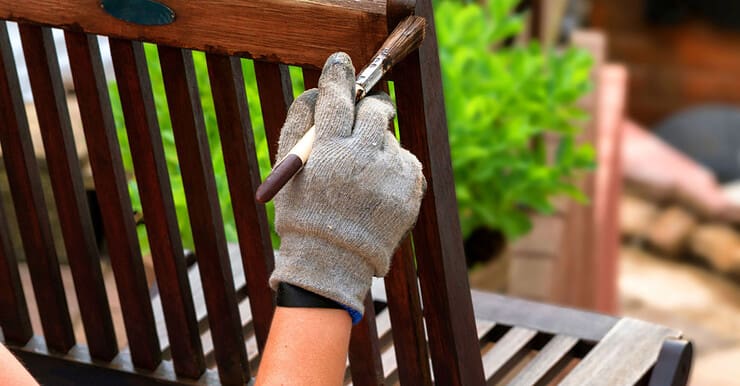 Main d’une personne peignant une chaise en bois