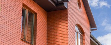 Vue sur la façade d'une maison avec des murs en briques rouges et des fenêtres vitrées