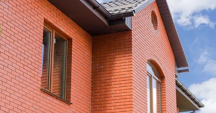 Vue sur la façade d'une maison avec des murs en briques rouges et des fenêtres vitrées