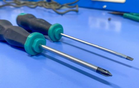 Deux tournevis noirs et verts de différents types posés sur une surface bleue
