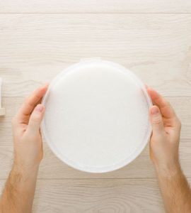 Mains d'un homme tenant un récipient rempli de colle pour papier peint