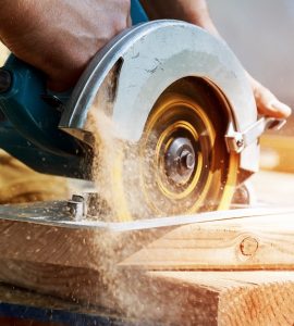 Un homme en train de couper une planche de bois avec une scie circulaire