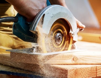 Un homme en train de couper une planche de bois avec une scie circulaire