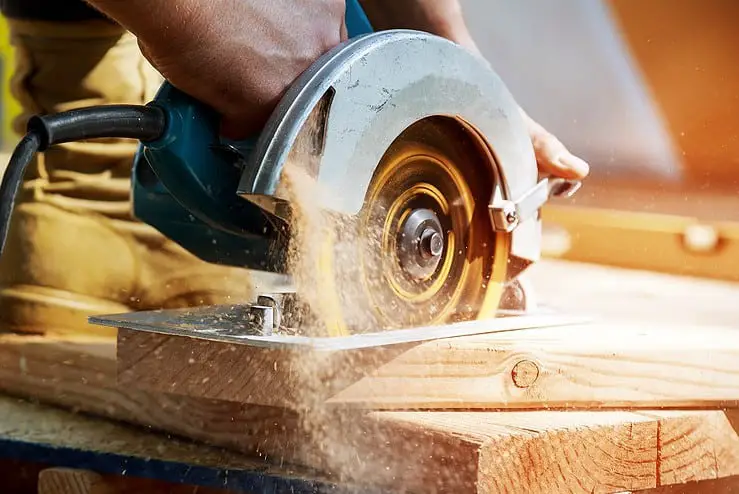 Un homme en train de couper une planche de bois avec une scie circulaire