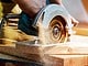 Un homme en train de couper une planche de bois avec une scie circulaire