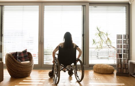 Une femme en fauteuil roulant dans une chambre avec baies vitrées