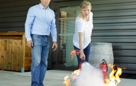 Une femme utilisant un extincteur pour éteindre un feu pendant qu’un homme le regarde