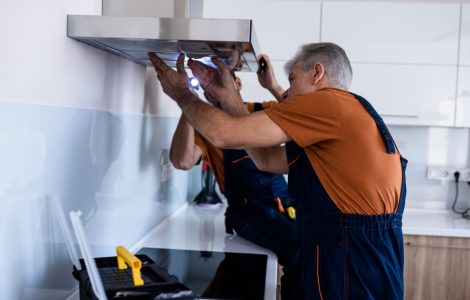 Deux hommes en combinaison installant un extracteur de cuisine