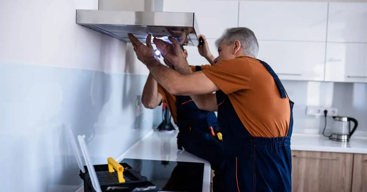 Deux hommes en combinaison installant un extracteur de cuisine