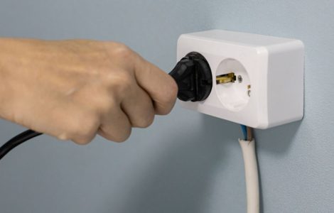 Zoom sur la main d'une personne mettant un cordon d'alimentation dans une prise électrique