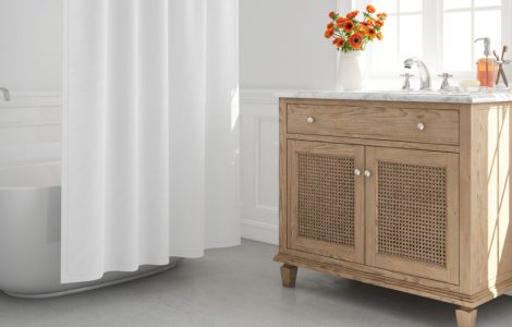 Une baignoire blanche avec rideau de douche et un petit meuble en bois dans une salle de bains