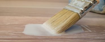 Focus sur un pinceau avec de la peinture coulant sur le parquet