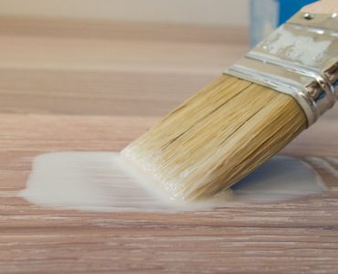 Focus sur un pinceau avec de la peinture coulant sur le parquet