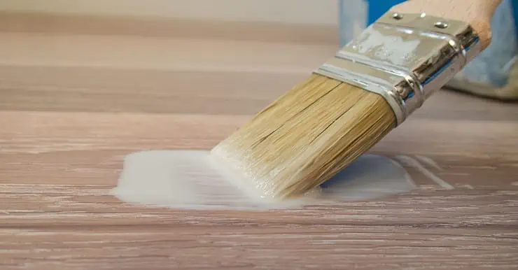 Focus sur un pinceau avec de la peinture coulant sur le parquet