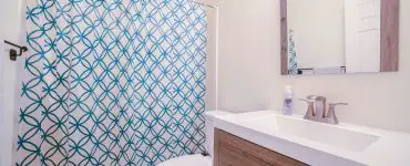 Une salle de bain avec un rideau de douche bleu et blanc