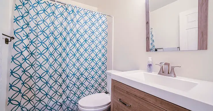 Une salle de bain avec un rideau de douche bleu et blanc