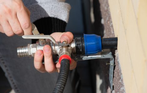 Zoom sur les mains d'une personne installent un robinet d'eau à l'extérieur