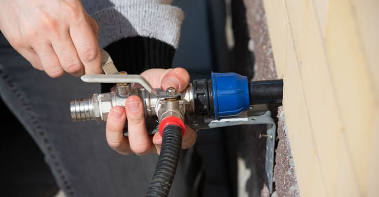 Zoom sur les mains d'une personne installent un robinet d'eau à l'extérieur