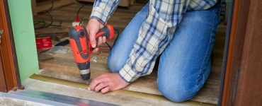 Un homme installe un seuil de plancher à l'aide de sa perceuse