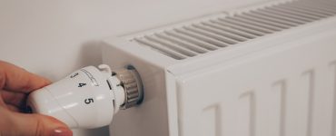 La main d'une femme tournant le thermostat du radiateur