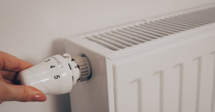 La main d'une femme tournant le thermostat du radiateur