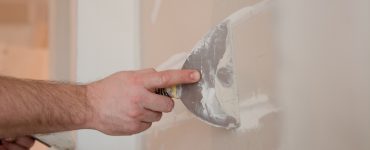 Un homme applique du plâtre sur un mur à l'aide de son outil