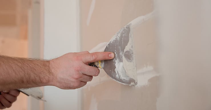 Un homme applique du plâtre sur un mur à l'aide de son outil