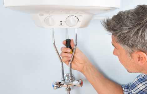Un homme répare le chauffe-eau