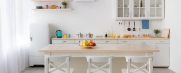 Une table à manger en bois et des chaises blanches dans une cuisine