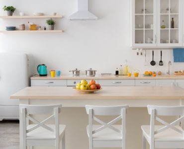 Une table à manger en bois et des chaises blanches dans une cuisine